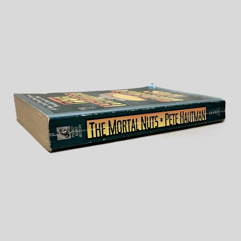 Close-up spine view of The Mortal Nuts by Pete Hautman centered on a neutral light gray background. Spine shows creasing.