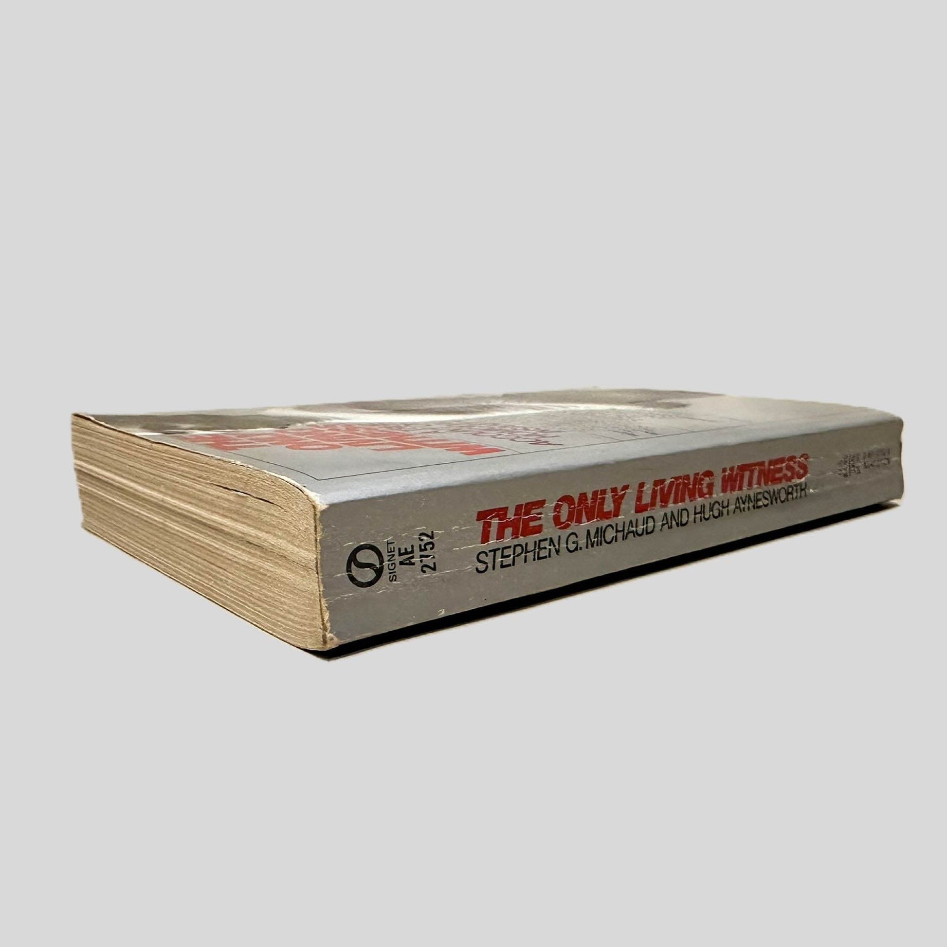 Close-up spine view of The Only Living Witness by Stephen G. Michaud & Hugh Aynesworth centered on a neutral light gray background. Spine shows creasing.