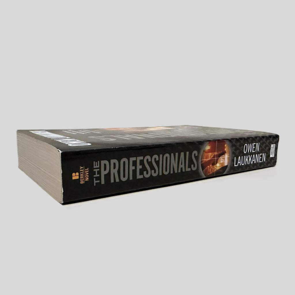 Close-up spine view of The Professionals by Owen Laukkanen centered on a neutral light gray background. Spine is square with no visible creasing.