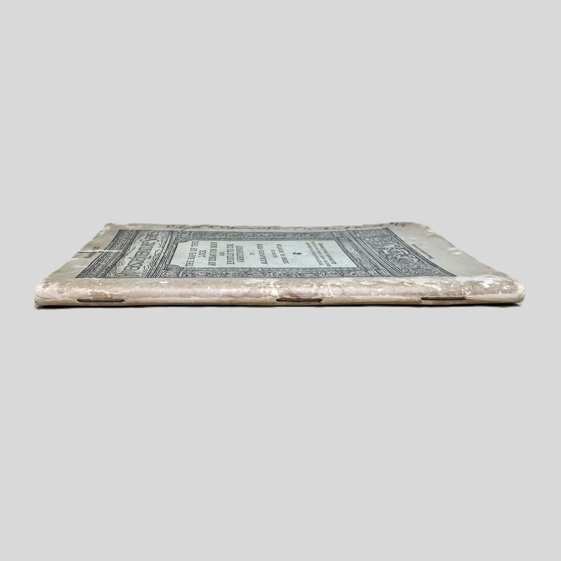 Close-up spine view of The Rape of the Lock by Alexander Pope centered on a neutral light gray background. 