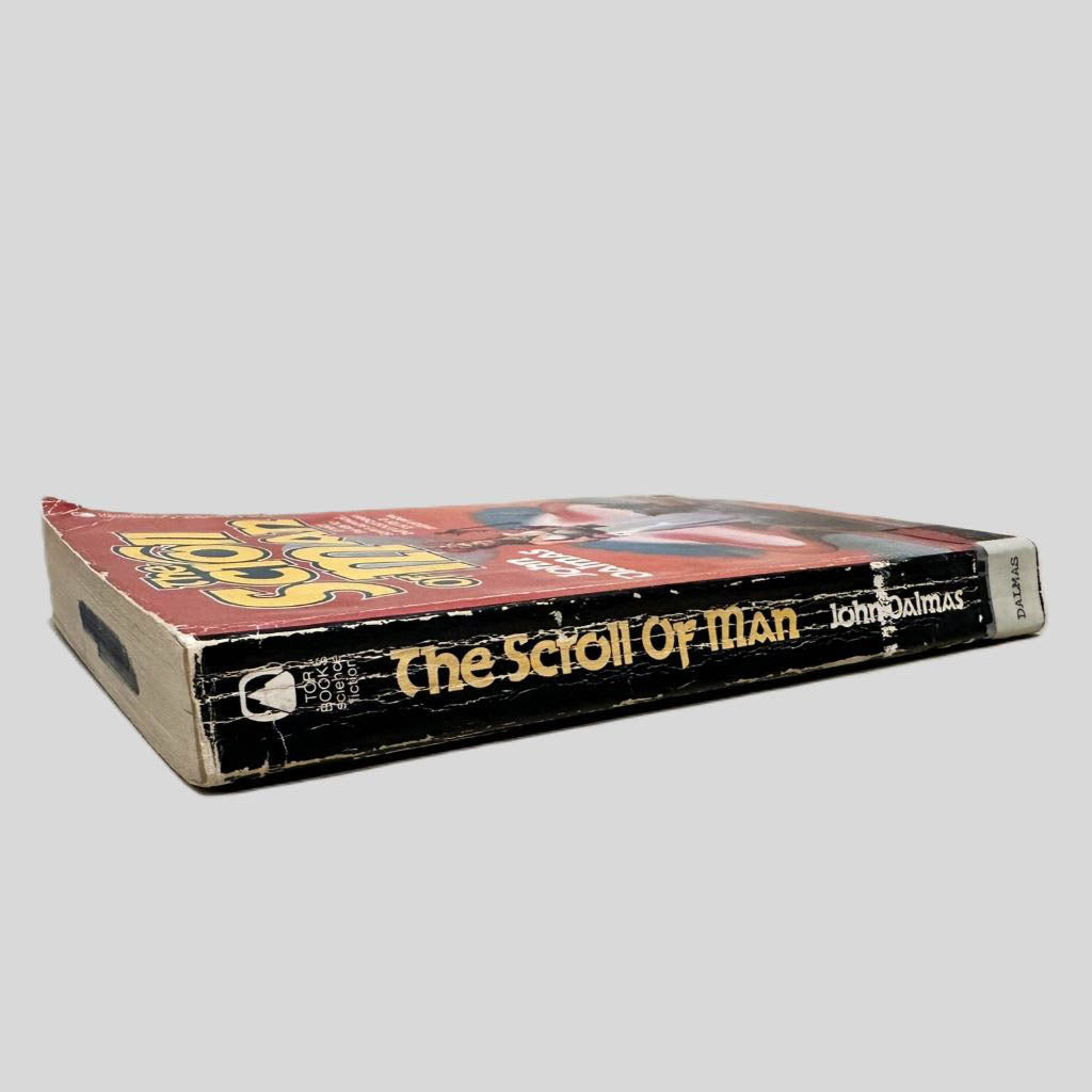 Close-up spine view of The Scroll of Man by John Dalmas centered on a neutral light gray background. Spine shows creasing. and chipping. Library catalog sticker attached to lower end of spine. Pages lay flat.