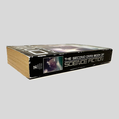 Close-up spine view of The Second Omni Book of Science Fiction centered on a neutral light gray background. Spine is square, shows rubbing on corners, no creasing. Pages lay flat.