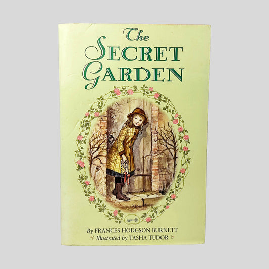 Front cover view of The Secret Garden by Frances Hodgson Burnett centered on a neutral light gray background. Dent on the front cover near the spine and top edge of cover. Cover art is vibrant.