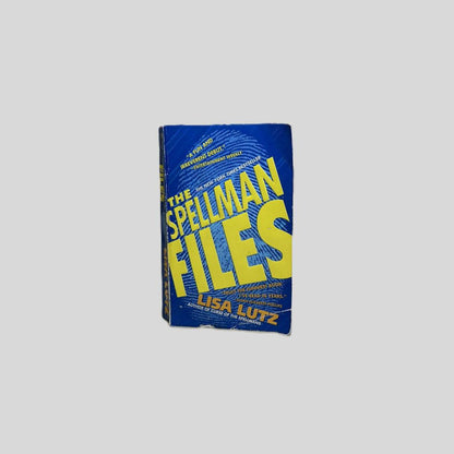 Front cover view of The Spellman Files by Lisa Lutz centered on a neutral light gray background. Chipping and creasing to the edges of the book. 
