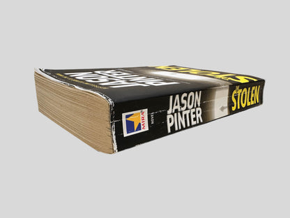 Close-up spine view of The Stolen by Jason Pinter centered on a neutral light gray background. Spine shows creasing. Pages lay flat.