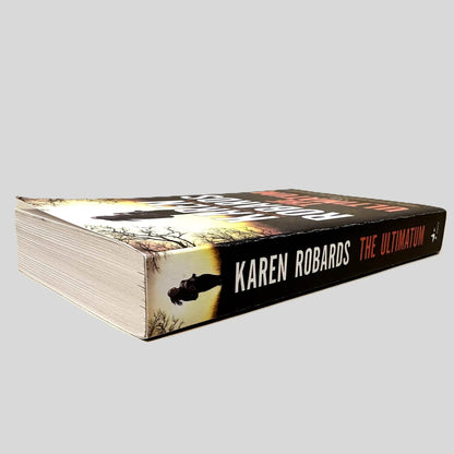 Close-up spine view of The Ultimatum by Karen Robards centered on a neutral light gray background. Spine shows minimal creasing.
