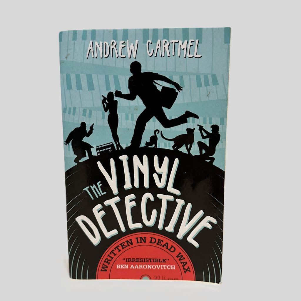 Front cover view of The Vinyl Detective by Andrew Cartmel centered on a neutral light gray background. 