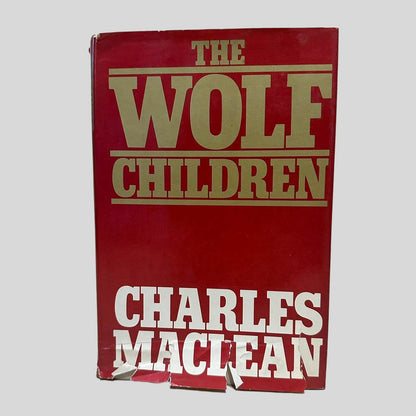 Front cover view of The Wolf Children by Charles Maclean centered on a neutral light gray background. Dust jacket is present. Significant tears to the bottom of the jacket.