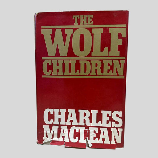 Front cover view of The Wolf Children by Charles Maclean centered on a neutral light gray background. Dust jacket is present. Significant tears to the bottom of the jacket.