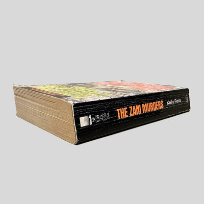 Close-up spine view of The Zani Murders by Kelly Fero centered on a neutral light gray background. Spine is square, shows creasing.