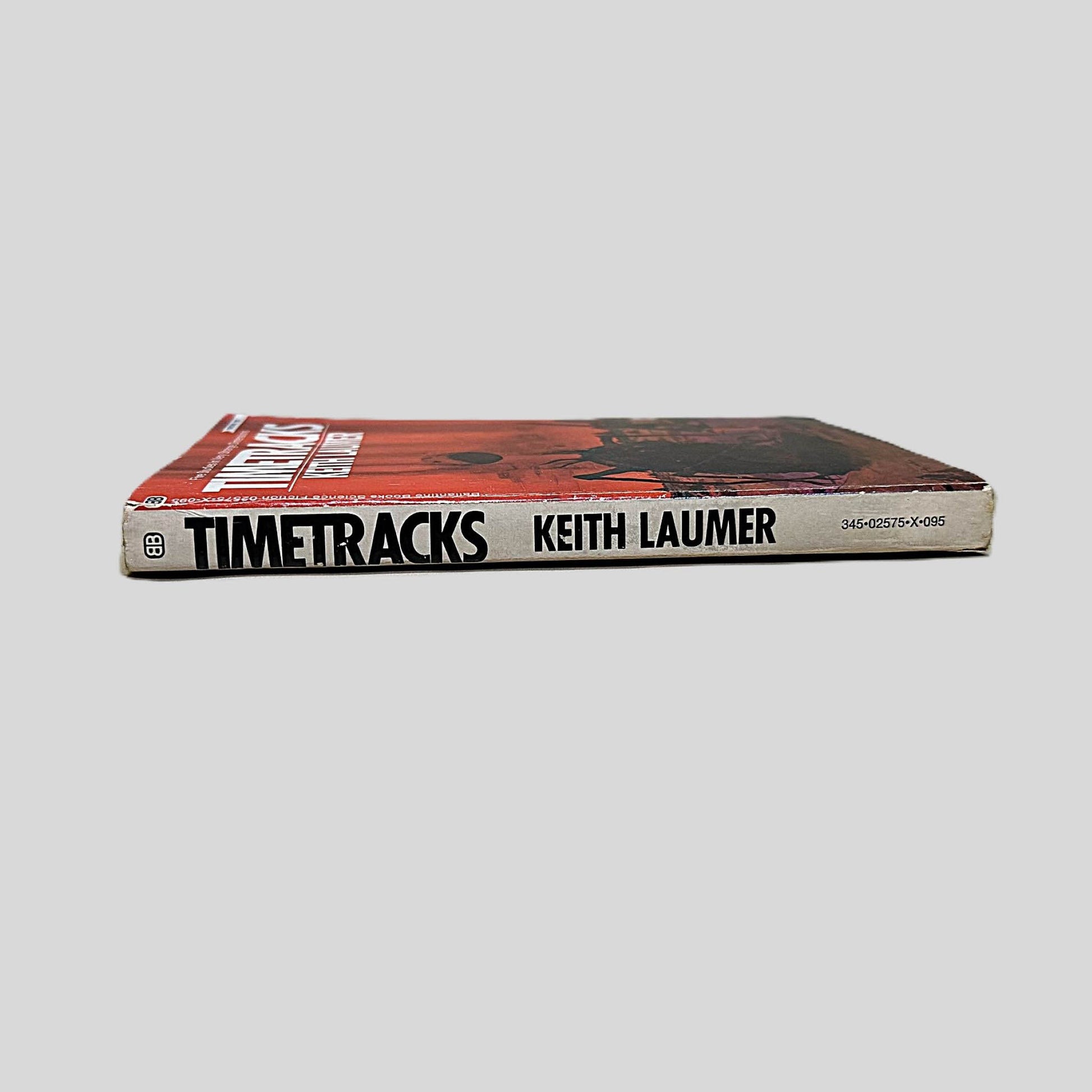 Close-up spine view of Timetracks by Keith Laumer centered on a neutral light gray background. Spine shows minimal creasing.