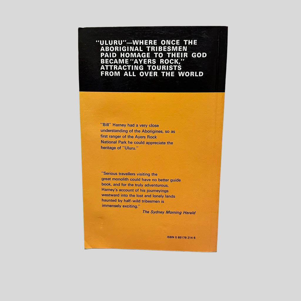 Back cover view of To Ayers Rock And Beyond by Bill Harney centered on a neutral light gray background. Crease in the bottom left corner. 