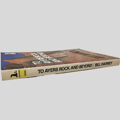 Close-up spine view of To Ayers Rock And Beyond by Bill Harney centered on a neutral light gray background. Spine shows no creasing and is square. Pages lay flat.