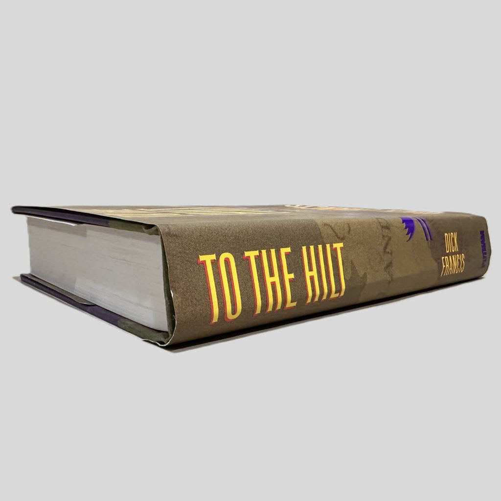 Close-up spine view of To the Hilt by Dick Francis centered on a neutral light gray background. Spine shows creasing. Dust jacket is present with no visible damage.