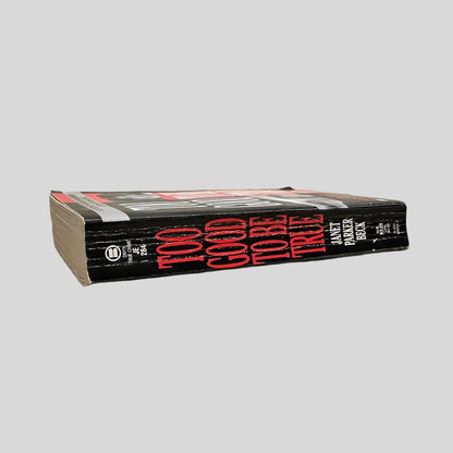 Close-up spine view of Too Good To Be True by Janet Beck centered on a neutral light gray background. Spine shows creasing.