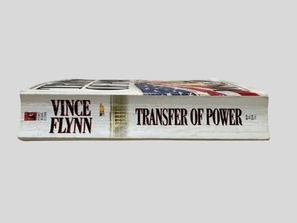 Close-up spine view of Transfer of Power by Vince Flynn centered on a neutral light gray background. Spine shows creasing.