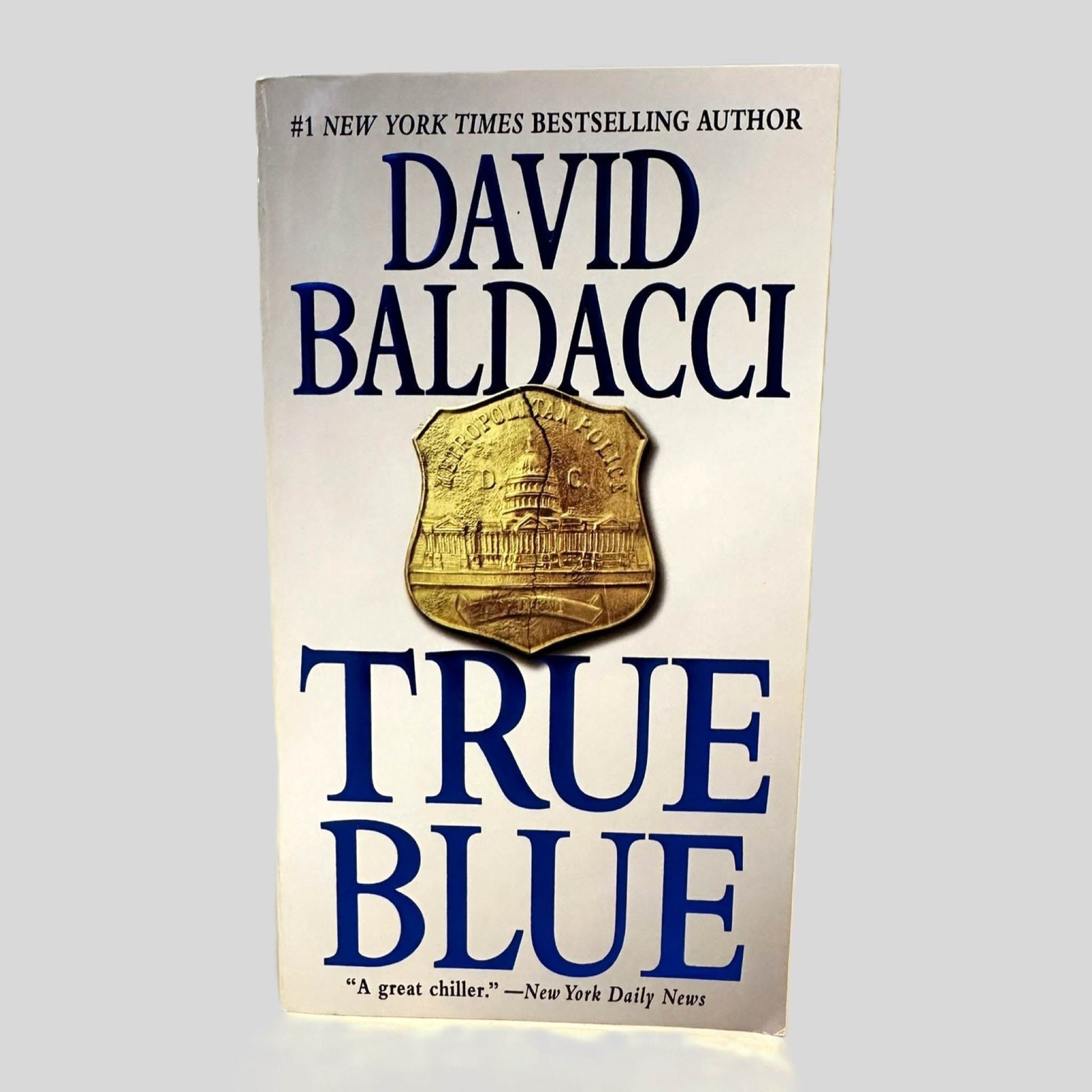 Front cover view of True Blue by David Baldacci centered on a neutral light gray background. 