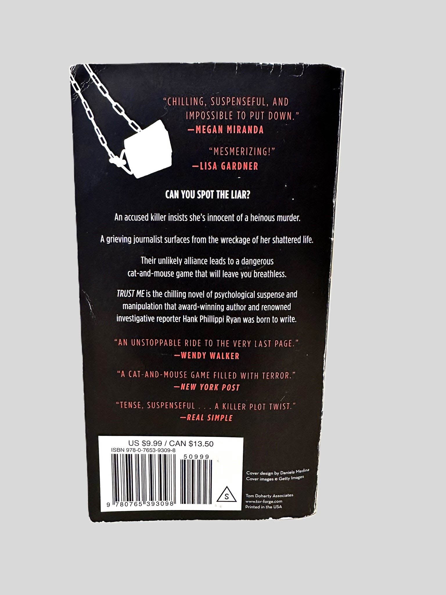 Back cover view of Trust Me by Hank Phillippi Ryan centered on a neutral light gray background. Chipping and creasing are present.