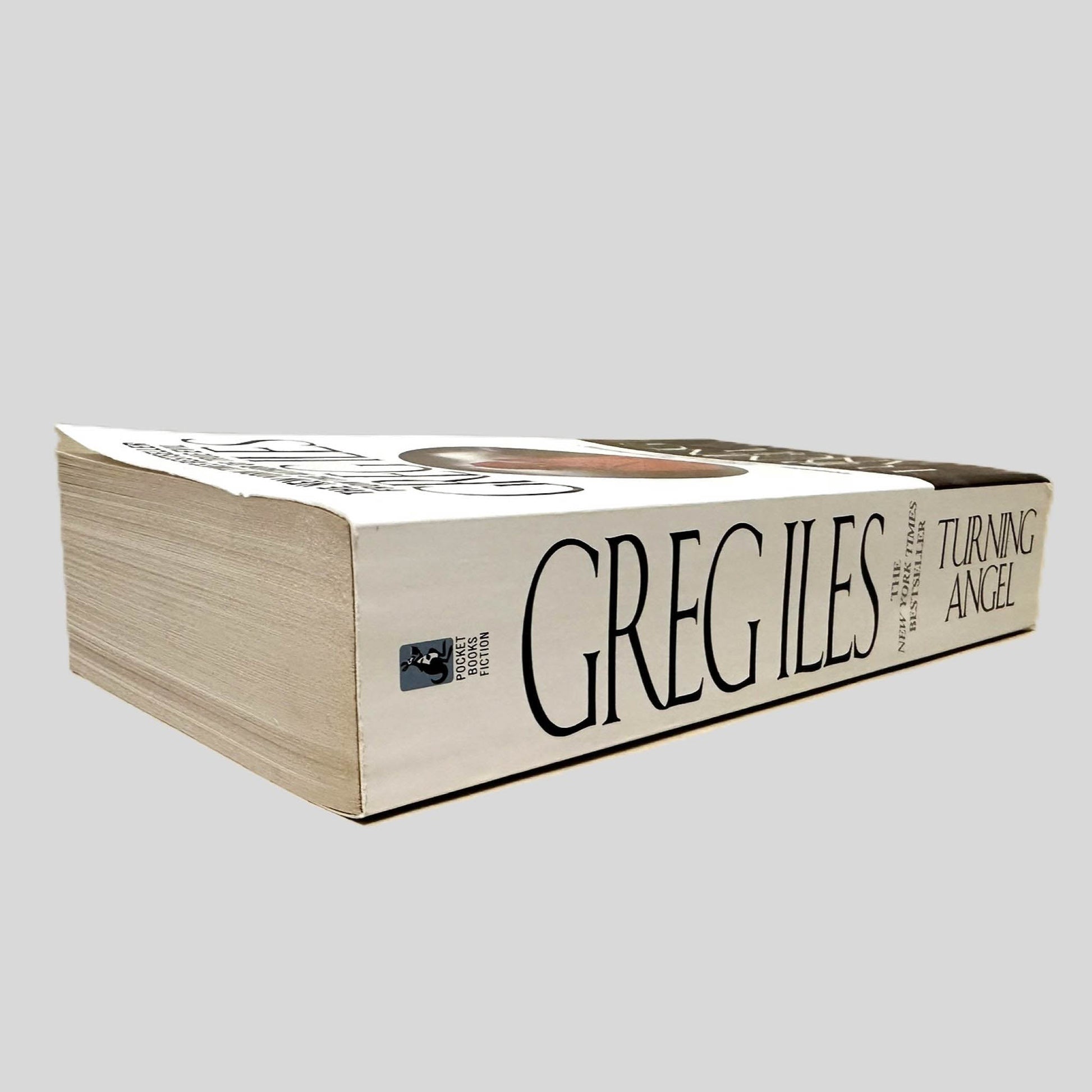 Close-up spine view of Turning Angel by Greg Iles centered on a neutral light gray background. Spine is square, shows no creasing. Pages lay flat.