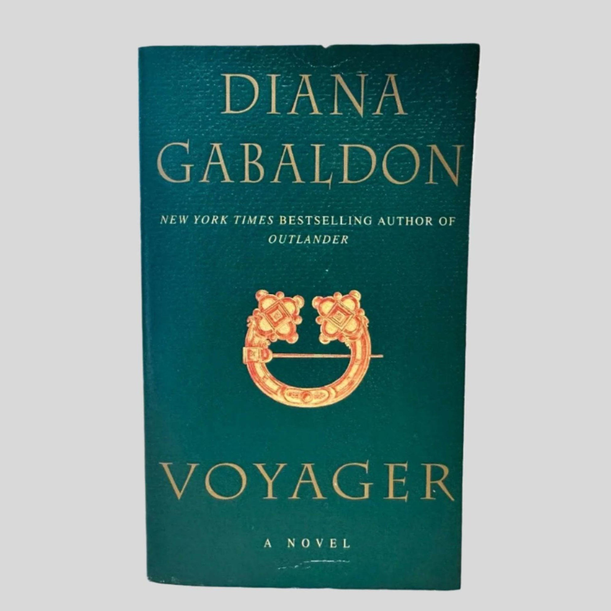 Front cover view of Voyager by Diana Gabaldon centered on a neutral light gray background. Minor chip on the top edge. Cover art is vibrant.