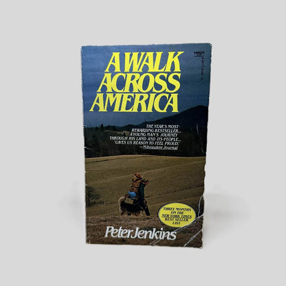 Front cover view of Walk Across America by Peter Jenkins centered on a neutral light gray background. Creasing and chipping on the lower right edges and corner. Cover art Is vibrant.