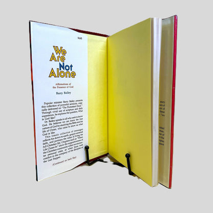 Inside front cover view of We Are Not Alone by Barry Bailey centered on a neutral light gray background. Dust jacket is present. Top corner of jacket is clipped but the price is not. Colors are vibrant and pages are crisp.