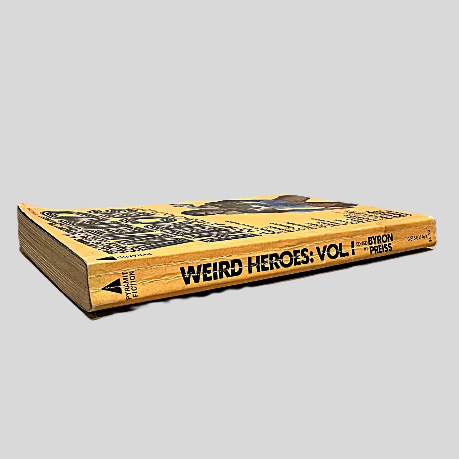 Close-up spine view of Weird Heroes, Vol. 1 Edited by Byron Preiss centered on a neutral light gray background. Spine shows creasing and chipping. Pages lay flat.