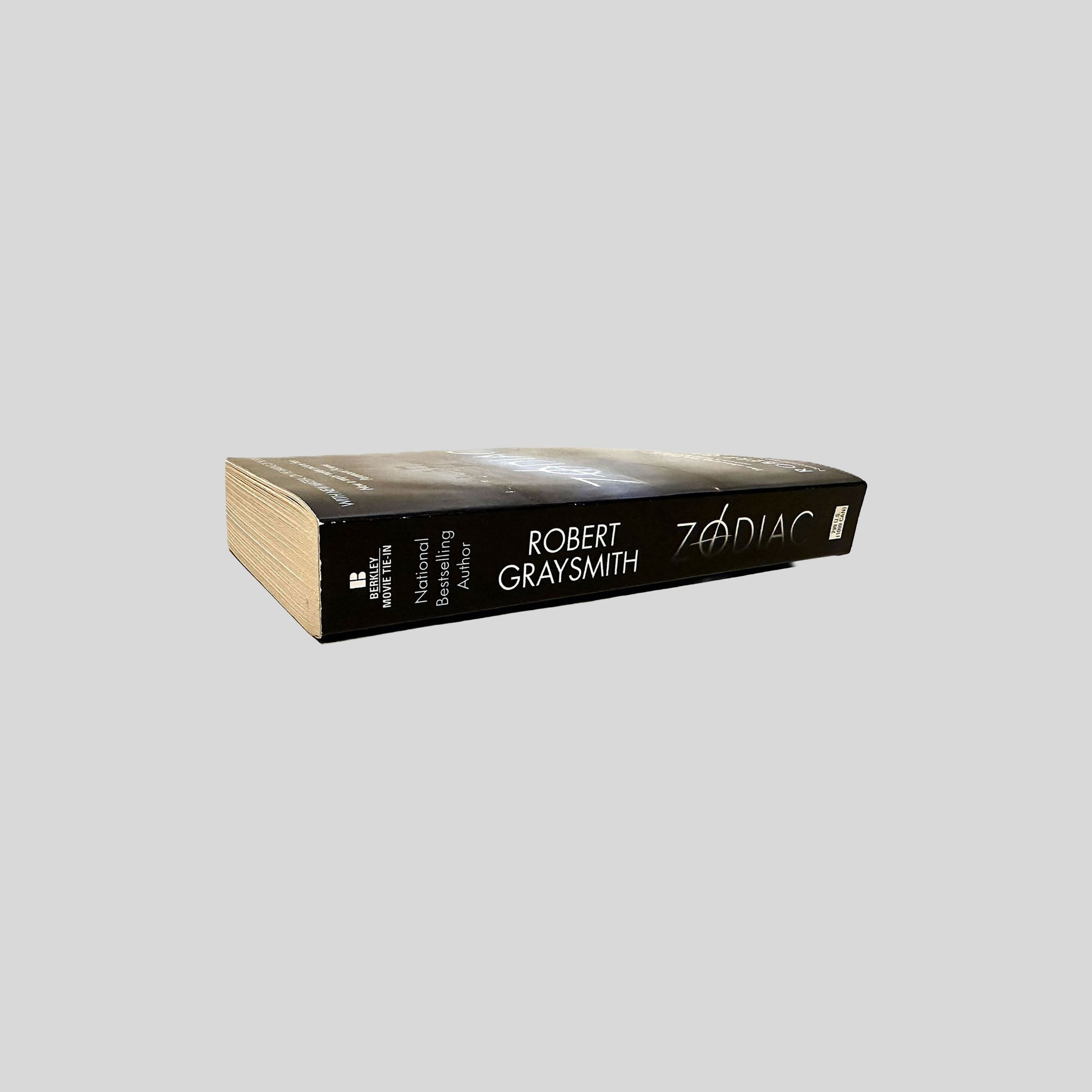 Close-up spine view of Zodiac by Robert Graysmith centered on a neutral light gray background. 
