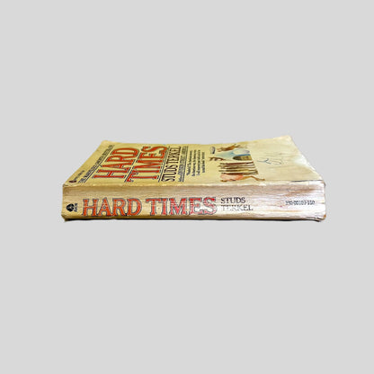Side-angle view of 'Hard Times' resting on a neutral background. The spine prominently displays the author's name in bold block letters and the Avon logo, reflecting the well-read condition of this Great Depression oral history classic. The screen captures the genuine vintage aging of this specific mass-market volume.