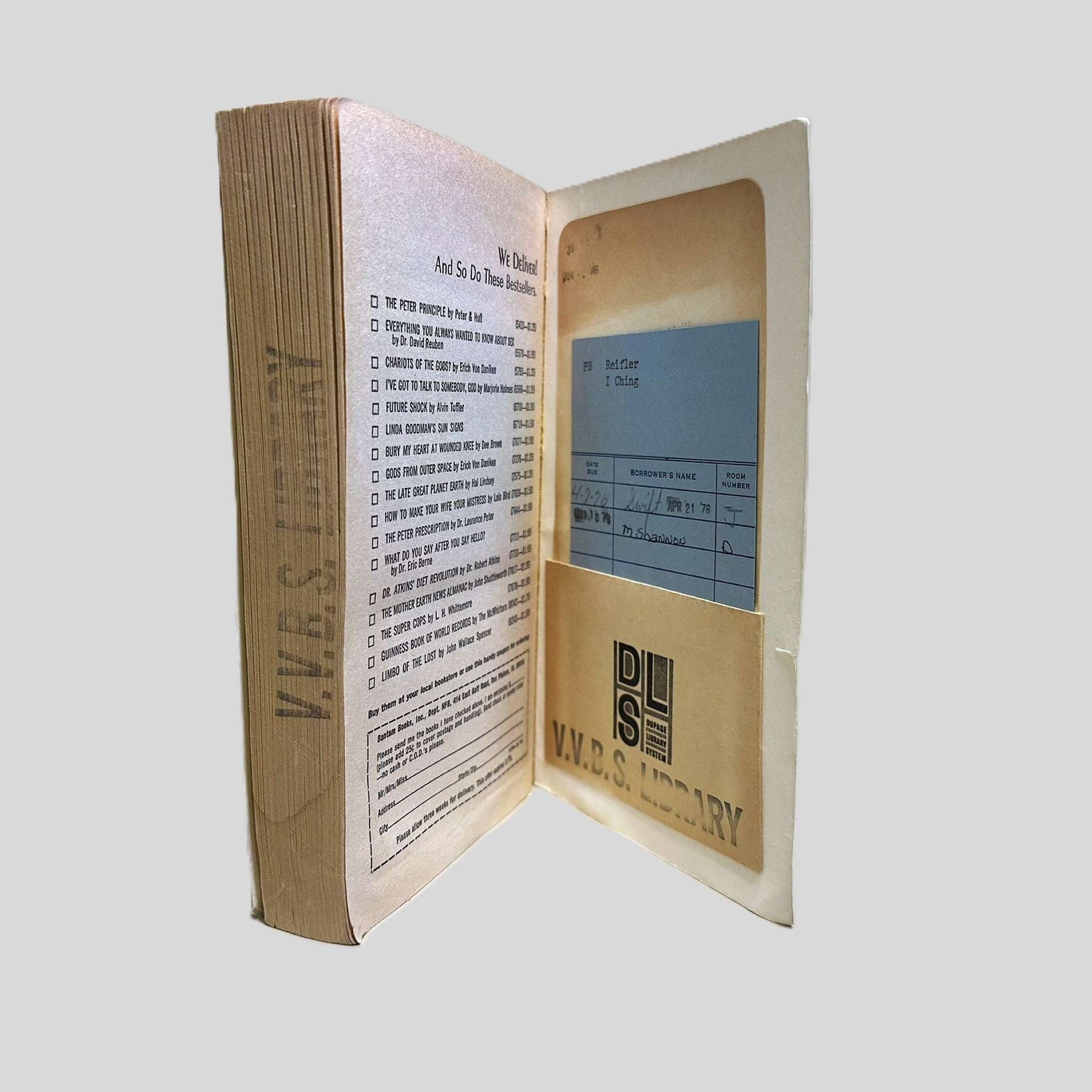 The inside front cover and first page of a vintage Bantam paperback edition of 'I Ching'. The image highlights the book's history as a former library copy, featuring a 'V.V.B.S. LIBRARY' stamp and a vintage checkout card tucked into a paper pocket. The first page lists other Bantam best-sellers, including works by Dr. David Reuben and Poul Anderson, reflecting its mid-century publishing context.