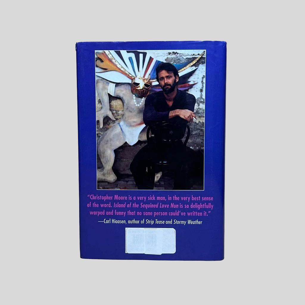 Back cover of the humorous fiction novel 'Island of the Sequined Love Nun' by Christopher Moore, featuring a blue border and a review blurb by Carl Hiaasen.