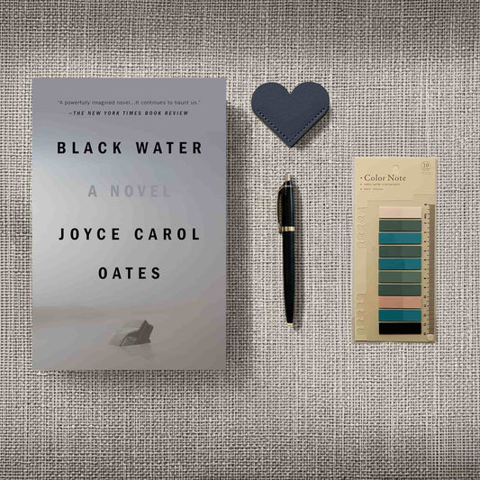 Joyce Carol Oates 'Black Water' novel flatlay with a vintage-style pen and aesthetic reading accessories on a textured background.