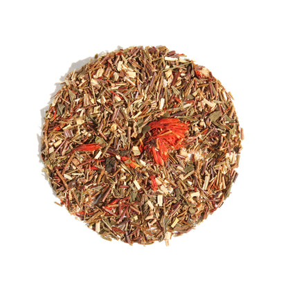 A close-up, overhead view of Plum Deluxe Candy Cane Herbal Tea arranged in a neat circle against a white background. The caffeine-free loose leaf blend features fine green rooibos and peppermint, highlighted by vivid red safflower petals.