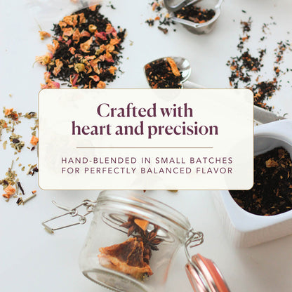 Various loose leaf tea blends, a heart-shaped measuring spoon, and a glass jar scattered on a white background. A text overlay reads: Crafted with heart and precision. Hand-blended in small batches for perfectly balanced flavor.