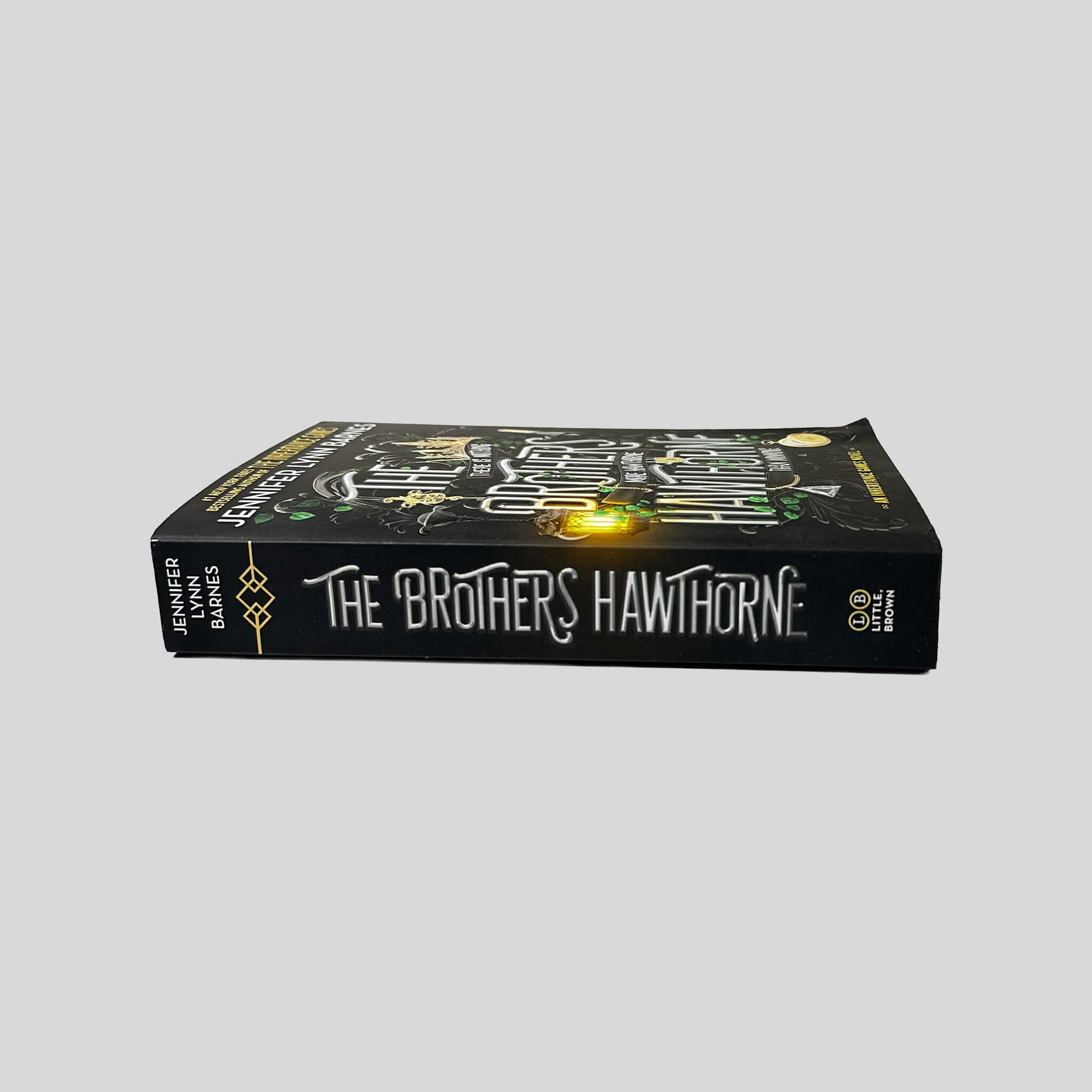 Unbroken spine view of The Brothers Hawthorne paperback by Jennifer Lynn Barnes displaying white title lettering, Little Brown publisher logo, crisp edges, and clean binding.