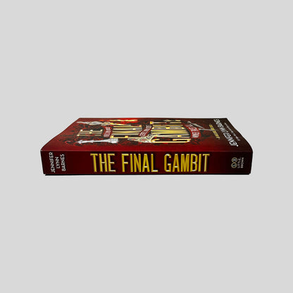 Unbroken spine view of The Final Gambit paperback by Jennifer Lynn Barnes displaying metallic gold title lettering, pristine edges, and clean binding.