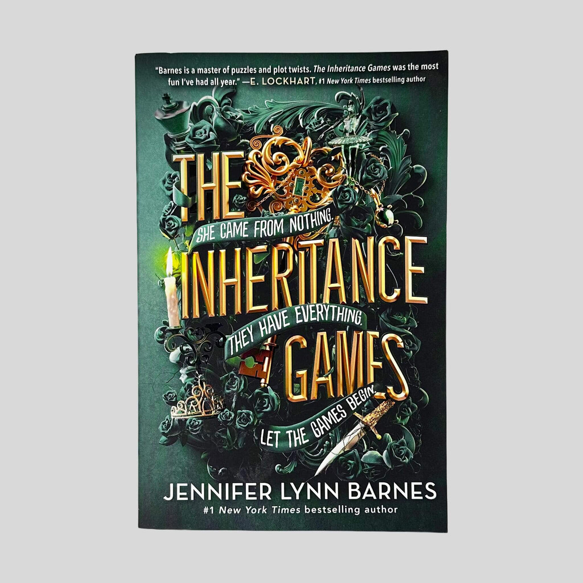 Front cover of The Inheritance Games by Jennifer Lynn Barnes in Like New paperback condition, featuring ornate green and gold key art with dark green roses.
