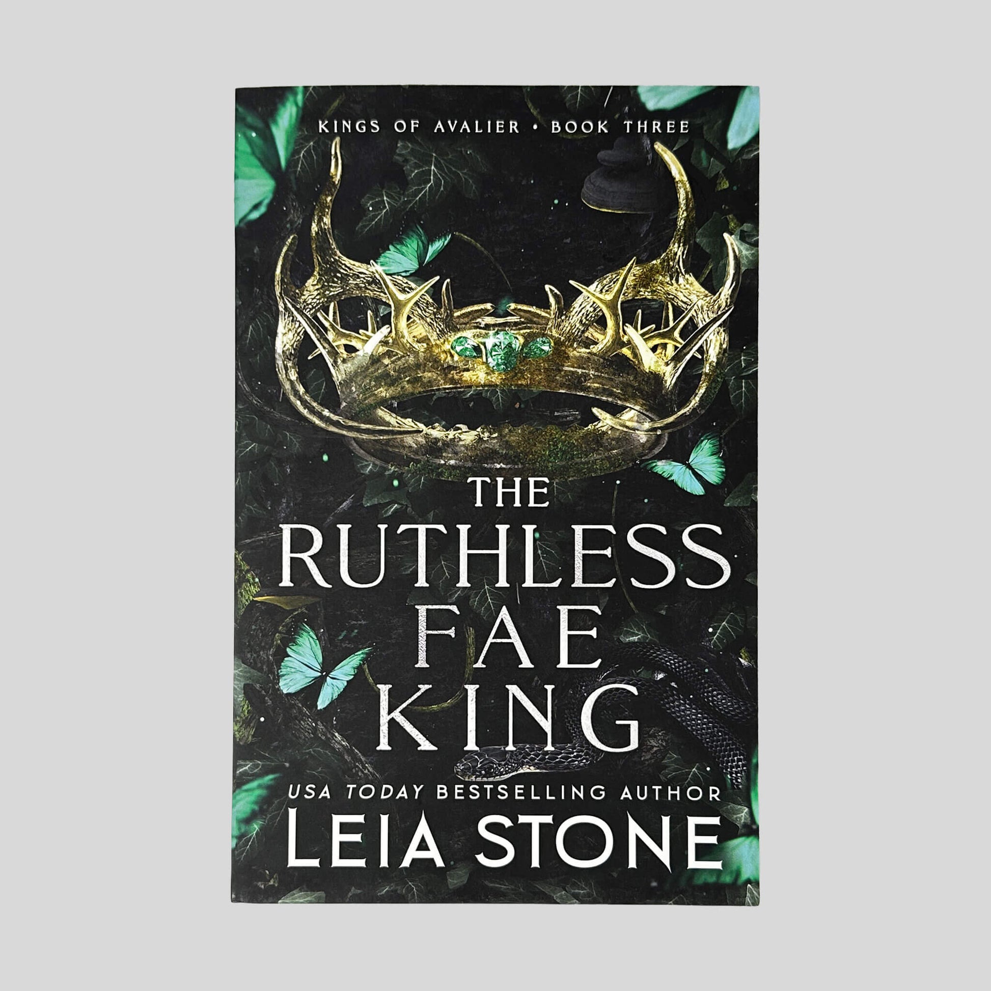 Front cover of The Ruthless Fae King by Leia Stone in Like New paperback condition, displaying Kings of Avalier Book Three header above a gold antler crown and teal butterflies.