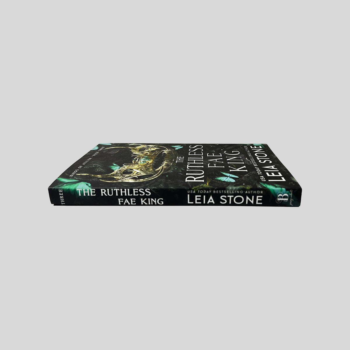 Unbroken spine view of The Ruthless Fae King paperback by Leia Stone displaying white title lettering, Kings of Avalier Book Three mark, and clean binding.