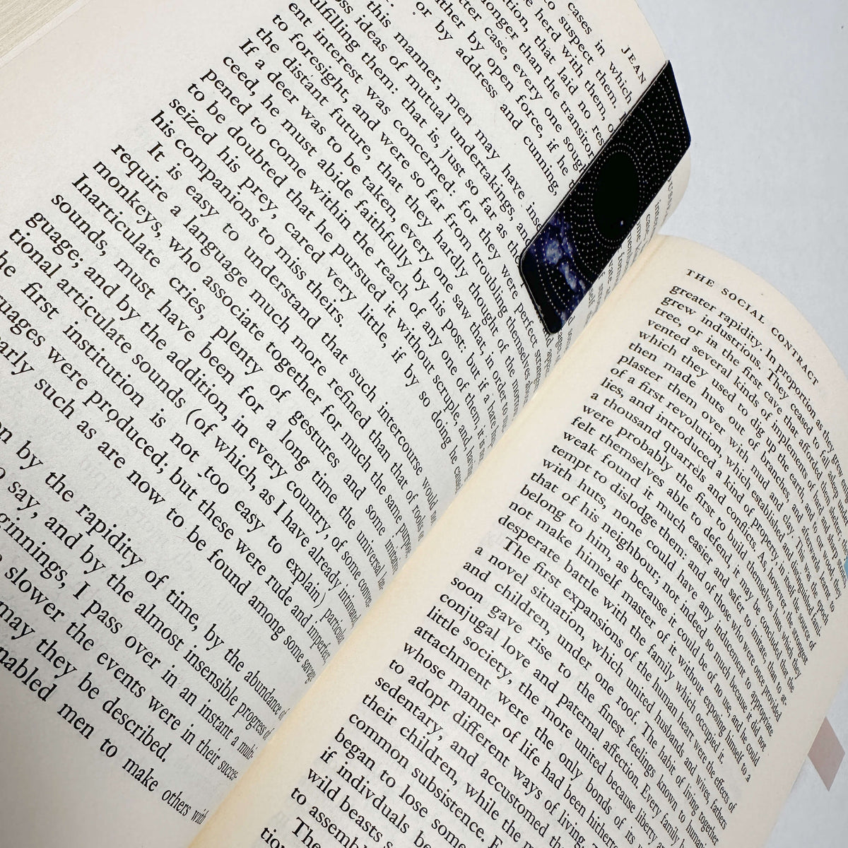 Close-up perspective of slim magnetic page clip hugging novel pages without paper damage by Fehmerling Books.