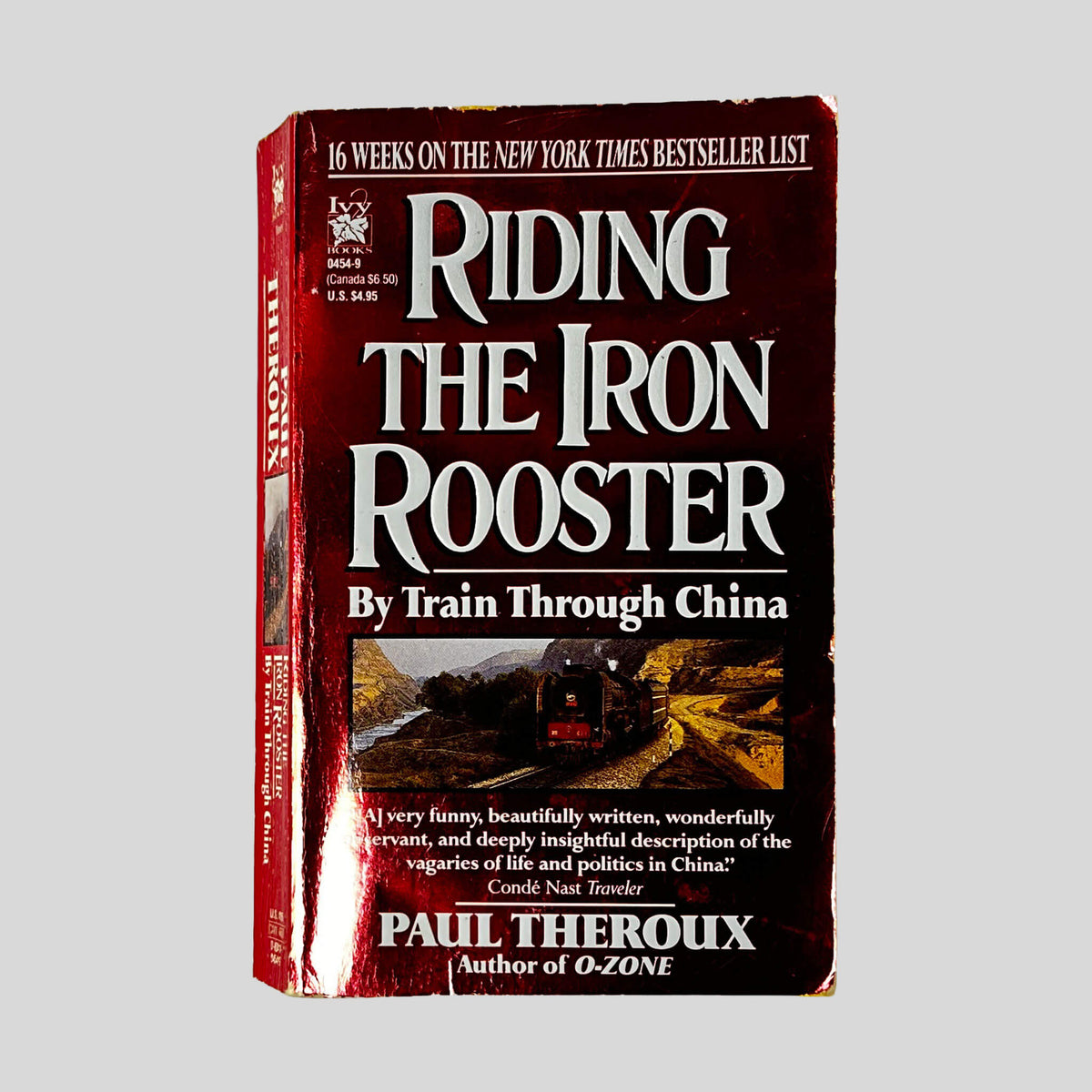 Front cover of Riding the Iron Rooster by Paul Theroux, vintage used paperback edition (Railroad travelogue).