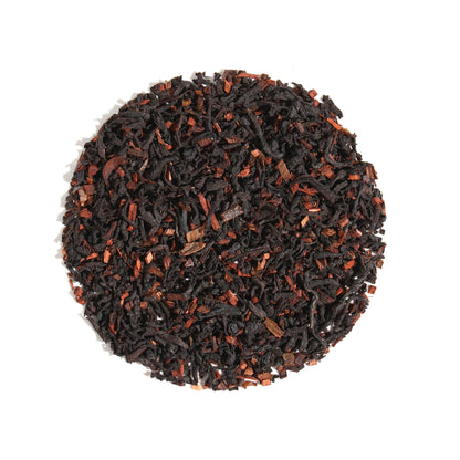 Top-down view of Vanilla Latte Cardamom Creme Black Loose Leaf Tea arranged in a circle on a white background, displaying dark black tea leaves blended with aromatic cardamom and warm spice pieces.