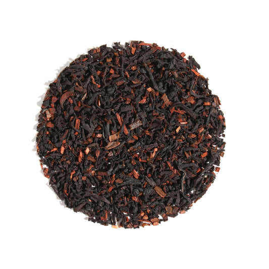 Top-down view of Vanilla Latte Cardamom Creme Black Loose Leaf Tea arranged in a circle on a white background, displaying dark black tea leaves blended with aromatic cardamom and warm spice pieces.